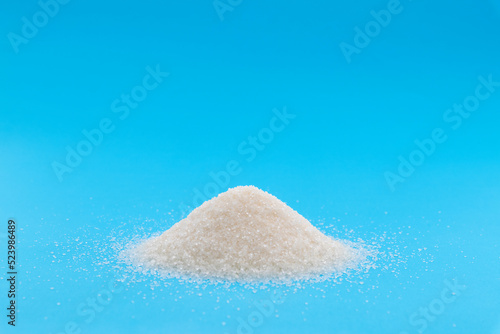 Pile of white sugar crystals on blue background