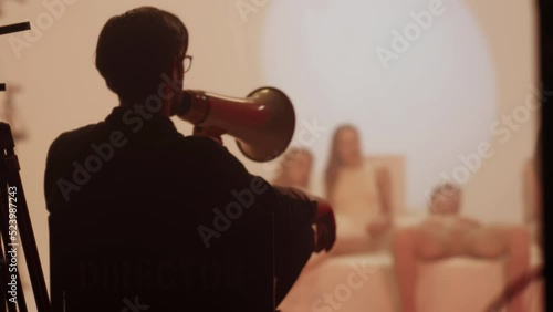 A male director on the set shouts into a megaphone to the actors