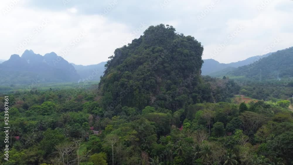An aerial rotational drone shot of the jungle landscape of Khao Sok National Park, with houses hidden under the trees in Thailand, in the continent of Asia on a cloudy day An aerial rotational drone shot of the jungle landscape of Khao Sok National Park, with houses hidden under the trees in Thailand, in the continent of Asia on a cloudy day
