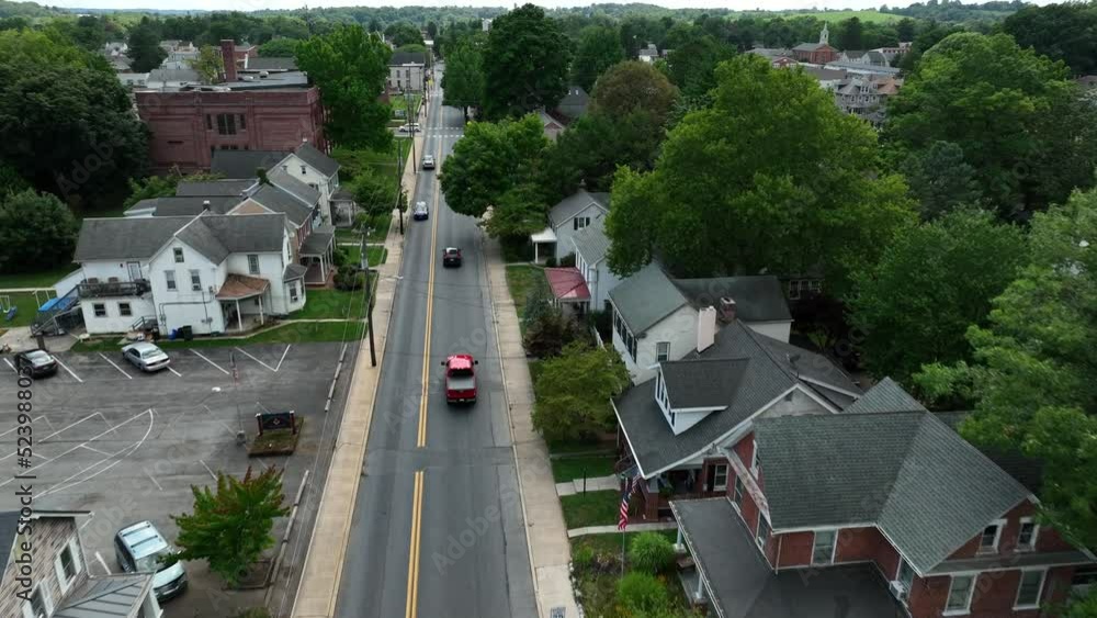 Tracking shot of trucks driving through American city. Aerial past church, school, houses, community buildings. Tracking shot of trucks driving through American city. Aerial past church, school, houses, community buildings.