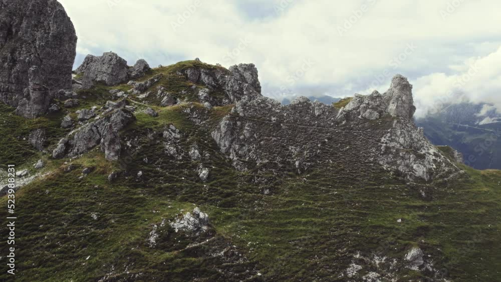 Beautiful aerial of alpine mountains 11er (Stubai, Austria). Stone formations with grass and a hiking trail near the peak. Alpine mountain scenery and a valley in the background on a sunny day. 4K Beautiful aerial of alpine mountains 11er (Stubai, Austria). Stone formations with grass and a hiking trail near the peak. Alpine mountain scenery and a valley in the background on a sunny day. 4K