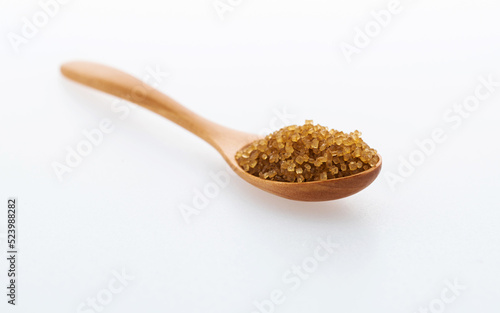 Wooden spoon of brown sugar on white background