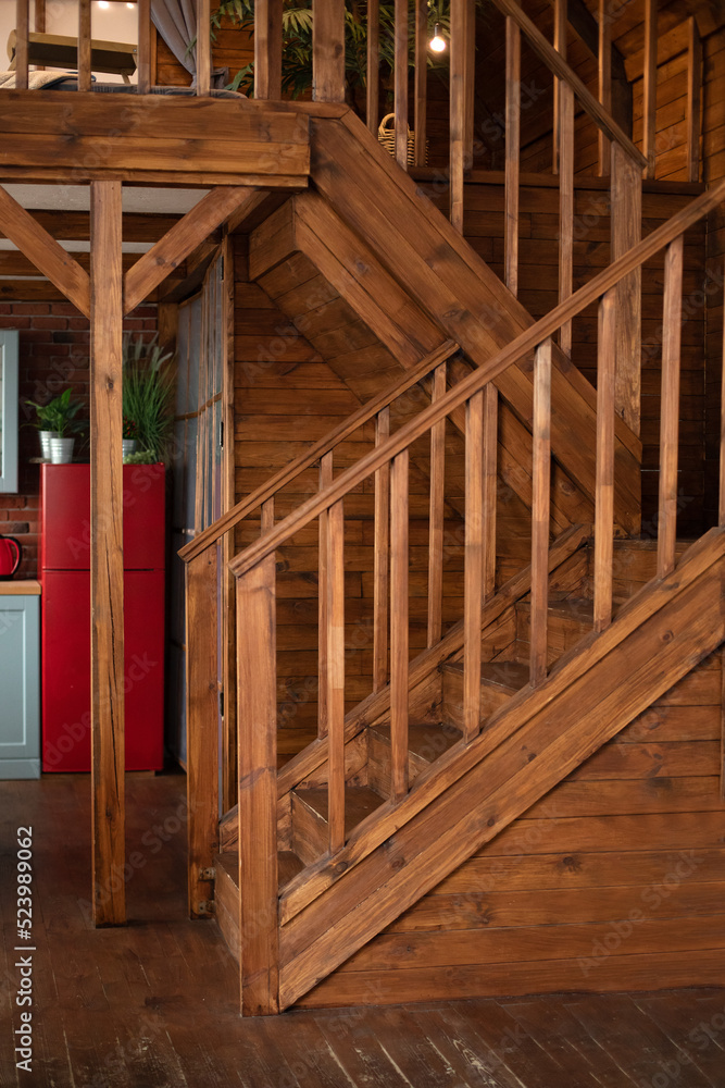 Wooden Stairway goes up. Country wooden house is spacious on two levels. Room with wooden stairway leading to second floor of modern flat. Modern staircase with wooden steps in flat. Wooden Stairway goes up. Country wooden house is spacious on two levels. Room with wooden stairway leading to second floor of modern flat. Modern staircase with wooden steps in flat.