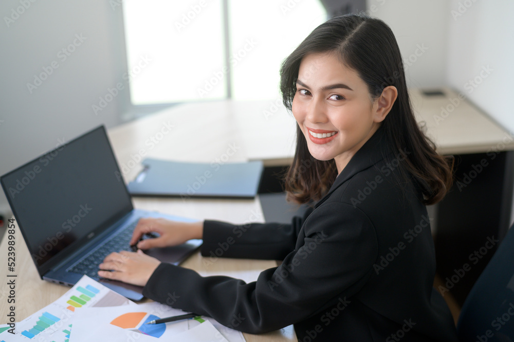 Young beautiful business woman working on laptop with documents in modern office Young beautiful business woman working on laptop with documents in modern office