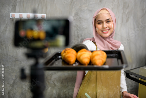 Canvas Print Beautiful muslim woman is making bakery while live streaming or recording video on social media in her house, coffee shop business concept