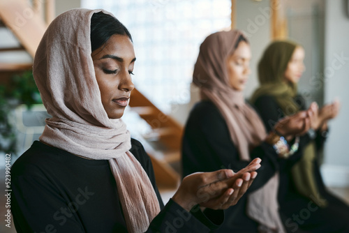 Fotografija Praying, muslim and young women group practicing arabic, holy and islamic religion indoors