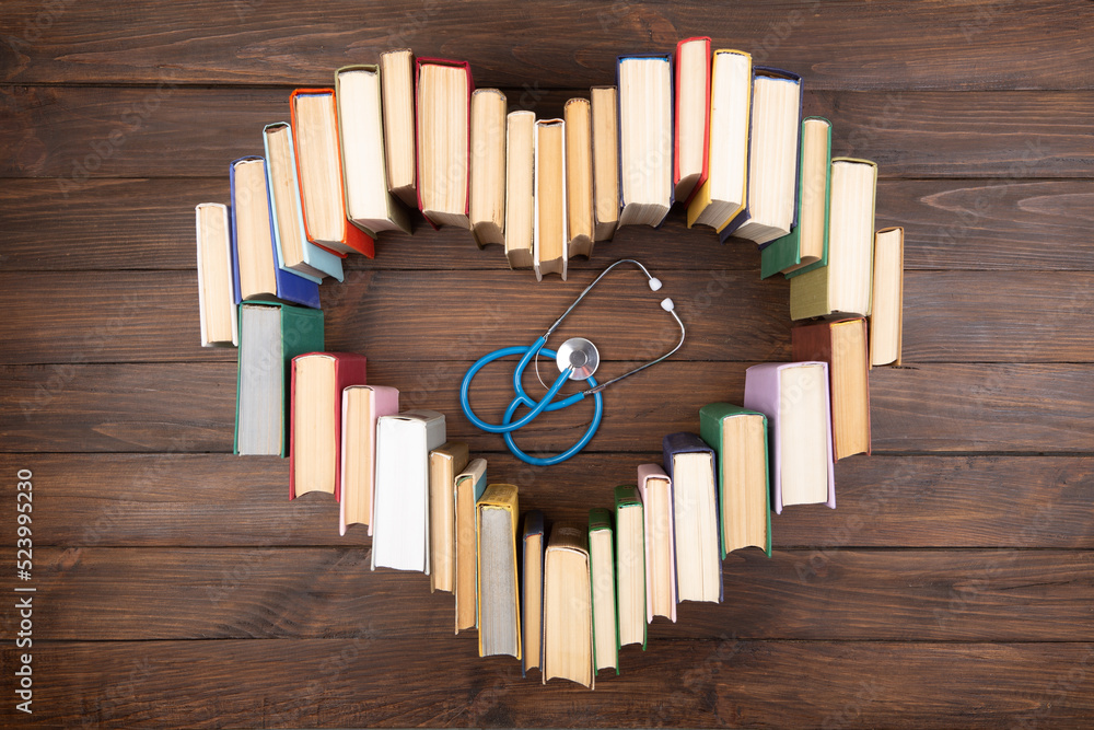 Medical degree education concept - stack of books in heart shape and stethoscope on the library table. Love to study medicine Medical degree education concept - stack of books in heart shape and stethoscope on the library table. Love to study medicine