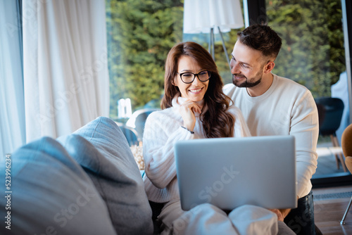 Happy couple relaxing together at home and using laptop