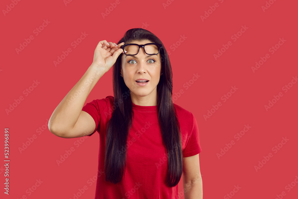 Portrait of stunned young woman isolated on red studio background take off glasses shocked by amazing sale offer or deal. Amazed female surprised with unbelievable news or discount. Wow face. Portrait of stunned young woman isolated on red studio background take off glasses shocked by amazing sale offer or deal. Amazed female surprised with unbelievable news or discount. Wow face.