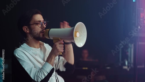 A male director on the set shouts into a megaphone to the actors