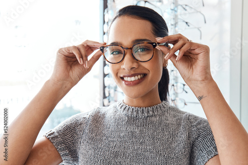 Fototapeta Naklejka Na Ścianę i Meble -  Glasses, vision and treatment by satisfied woman at optometrist, smiling and confident. Portrait of carefree female buying trendy spectacles to help with blurry vision, excited about her eyeglasses