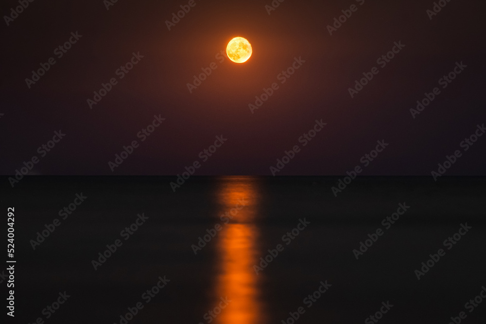 Full red moon landscape and its reflection over the sea. Moon photo at seaside.