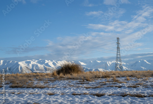 High voltage transmission towers and powerlines with snow-covered Ben Ohau range in the distance, Twizel, South Island. photo