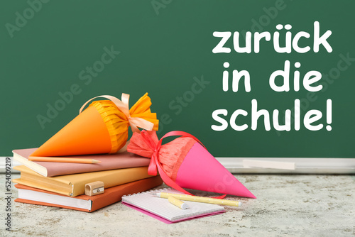 School cones, books and stationery on table in classroom. Zuruck in die schule (Back to school) photo