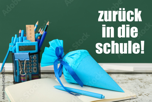 School cone and stationery on table in classroom. Zuruck in die schule (Back to school) photo