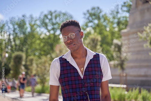 portrait of young African-American man wearing vest and shirt with glasses in the street