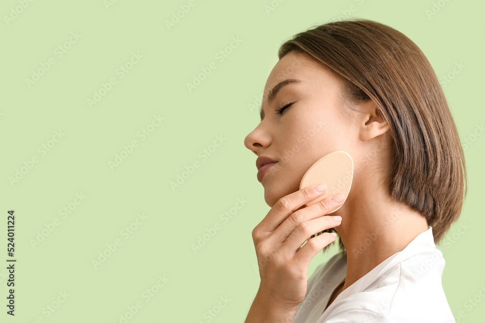 Pretty young woman with makeup sponge on green background, closeup Pretty young woman with makeup sponge on green background, closeup