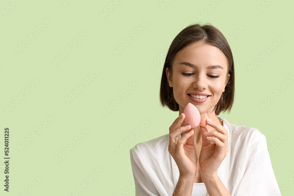 Pretty young woman with makeup sponges on green background Pretty young woman with makeup sponges on green background