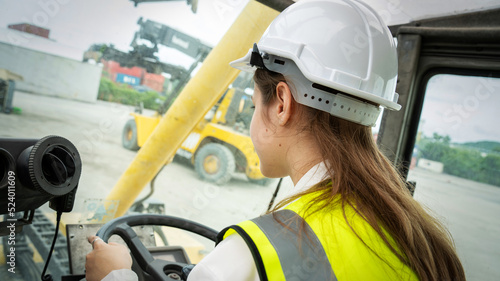 Female Foreman Drive a forklift container cargo forklift and use walkie talkie for communication during Driveing control forklift concept service and transportation logistic.