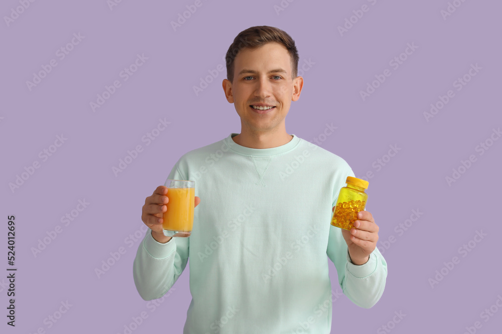 Young man with glass of juice and pill bottle on violet background Young man with glass of juice and pill bottle on violet background