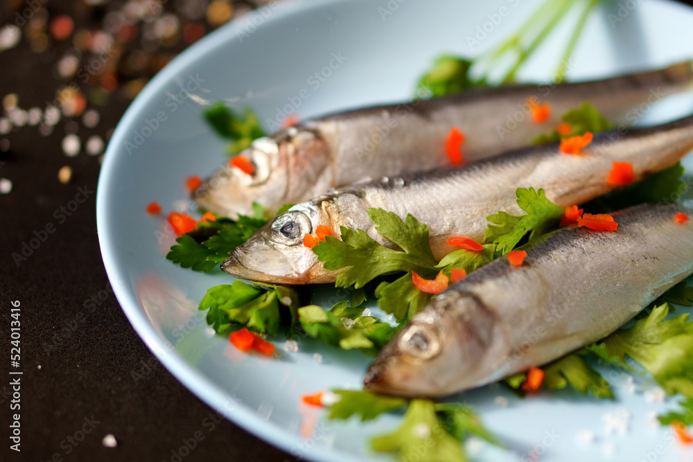 Blue plate with fried herring on a black background.