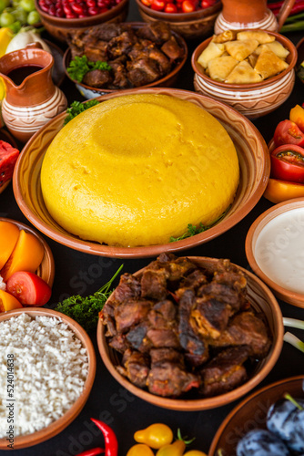 Homemade Romanian Food with polenta, meat, cheese and vegetables. Delicious corn porridge in clay dishes. Mamaliga or polenta, a traditional dish in Moldova, Hungary and Ukrainian cuisine. 