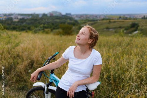 A beautiful woman on a bicycle is watching the clouds float on a warm summer evening