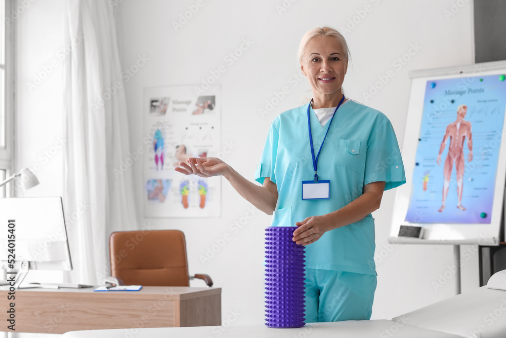 Fototapeta premium Mature physiotherapist with foam roller in rehabilitation center
