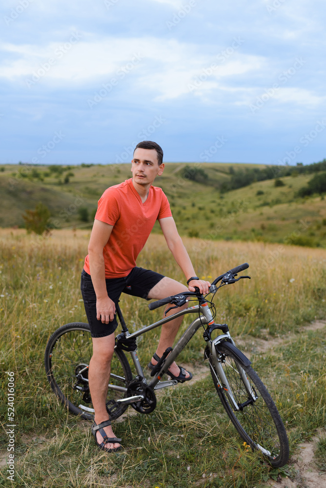 A young man on a bicycle is standing in the middle of the path, waiting to go further. A young man on a bicycle is standing in the middle of the path, waiting to go further.