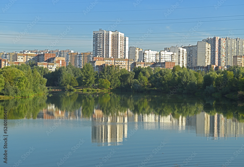Reflection of houses and buildings in Penyaginsky lake in Mitino Landscape Park. Moscow, Russia