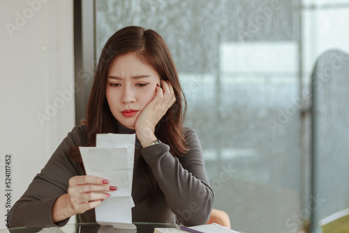 young woman look at pay bill holding ache at work. Tired woman employee looking at report on paper having headache. Stressful business deal concept