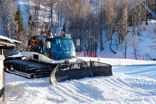 Winter sports european alps. View of a snow groomer in the mountains