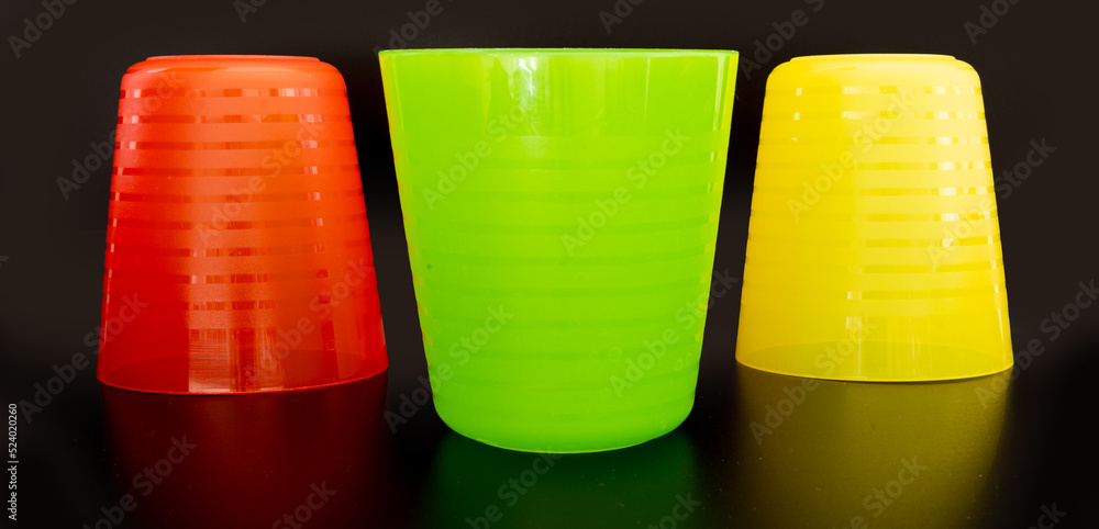 Plastic cups in red, yellow and green isolated on black background Plastic cups in red, yellow and green isolated on black background