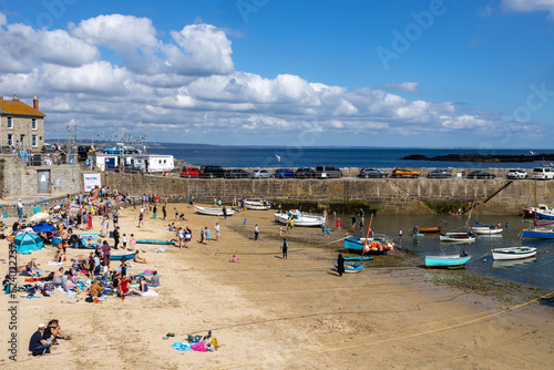 Blick auf den Strand im Hafen von The Mousehole, Cornwall, Sommer, blauer Himmel, Menschen sonnen und schwimmen photo