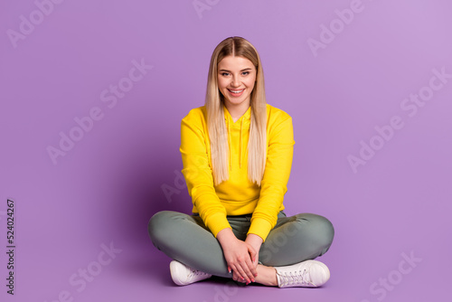 Full length photo of young cheerful lovely woman sit floor wear casual outfit isolated over violet color background