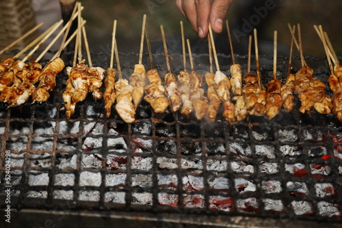 grilling skewered chicken meat on hot coal. chicken satay is one of indonesian traditional food. barbeque