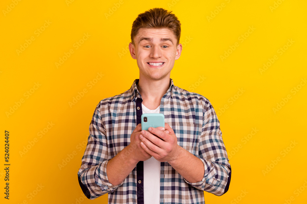 Photo of young cheerful man use mobile blogging comment like repost isolated over yellow color background Photo of young cheerful man use mobile blogging comment like repost isolated over yellow color background