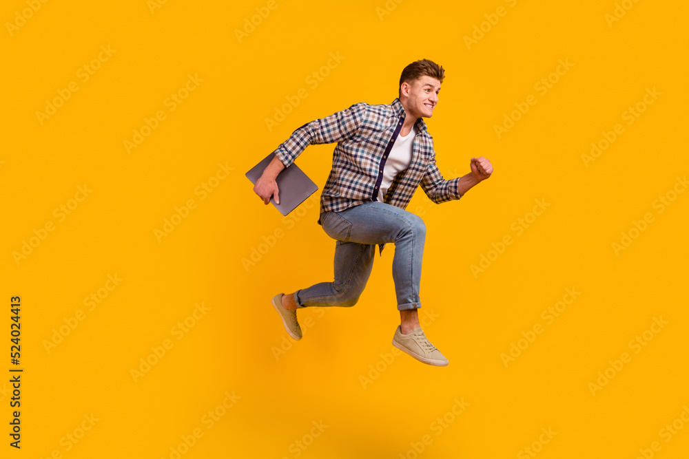 Full size profile side photo of young man jump run hold laptop manager isolated over yellow color background