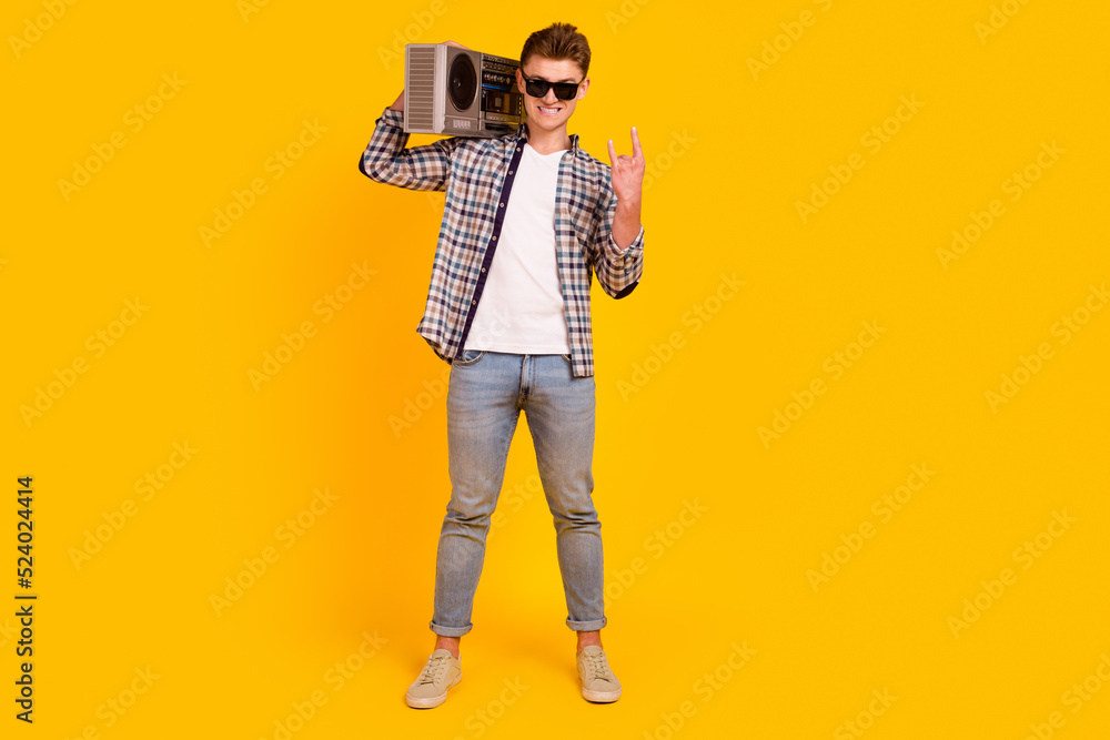 Full length photo of young man hold boombox music disco party retro isolated over yellow color background Full length photo of young man hold boombox music disco party retro isolated over yellow color background