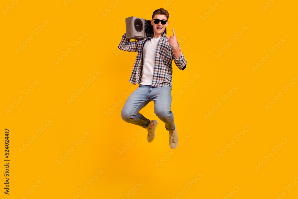 Full body photo of young man jump up energetic boombox music disco isolated over yellow color background