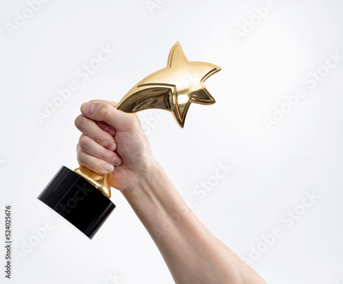 Human hand holding golden star trophy