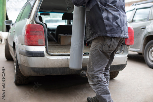 Man puts gas cylinder in trunk of car. Dangerous cargo in transport. © Олег Копьёв