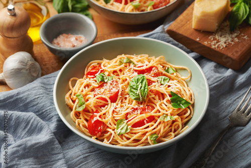 Plate of cooked spaghetti with cherry tomatoes and ingredients on the table