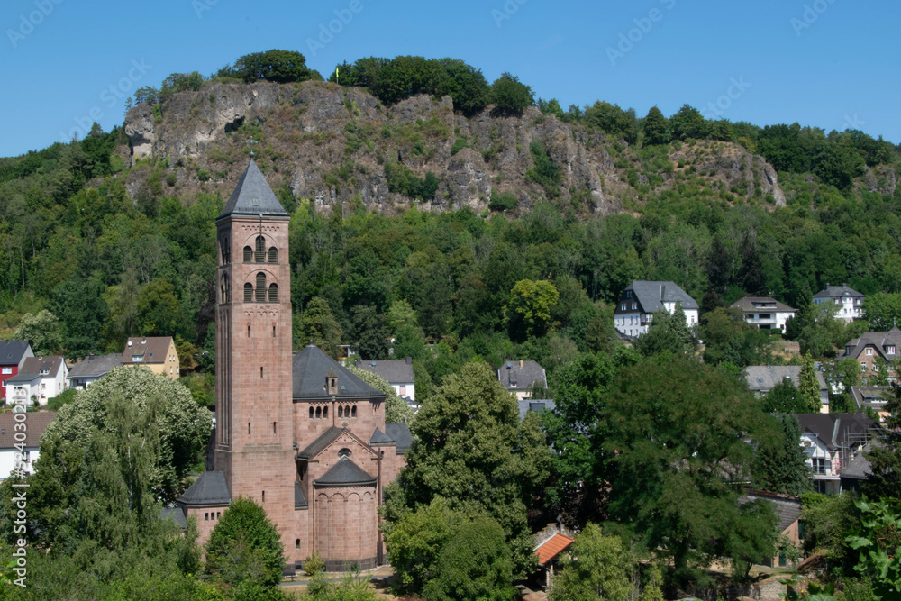 Church in the village of Gerolstein in the German Eifel with the rocks of the Gerolsteiner Dolomites in the background and the view point Munterley