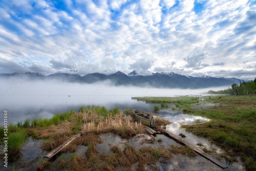 Landscape with mountains,fog,  lake and old wooden boat