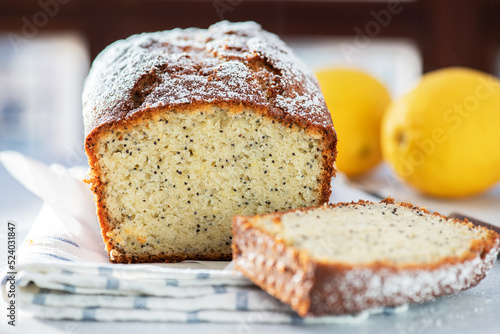Lemon cake with poppy seeds, sliced on a gray background.