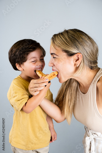 Mother and son enjoying and eating a Latin American snack called tequeños, funny expressions on their faces
