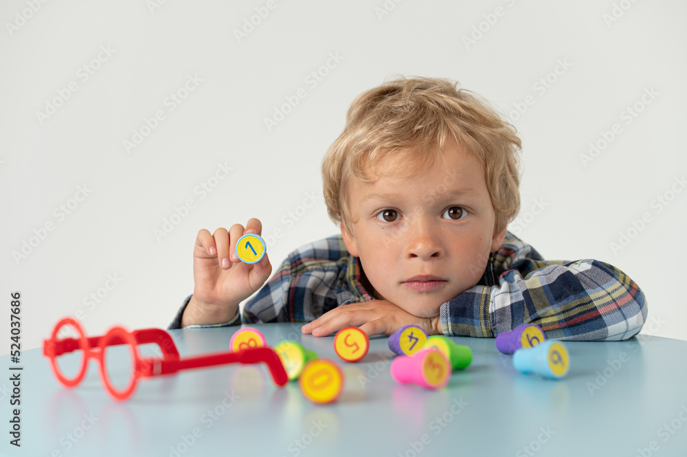 Boy sitting at a table, showing lotto number, school grade Boy sitting at a table, showing lotto number, school grade