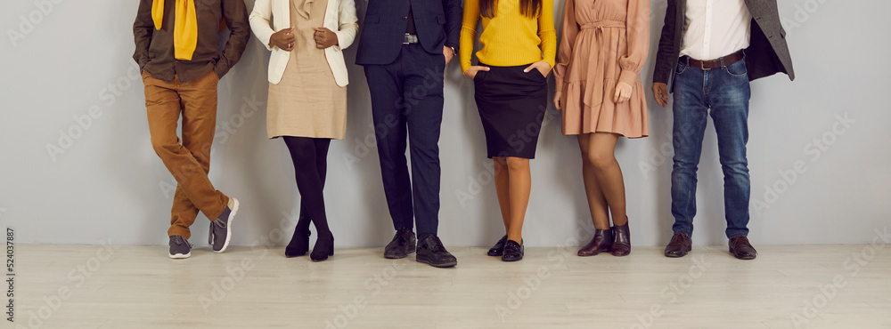 People in smart casual clothes by office wall. Row of company employees in  pants, skirts, jackets