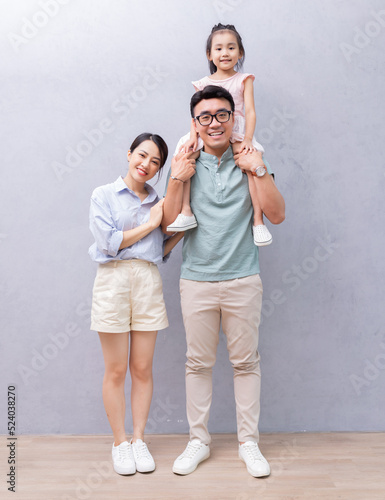 Young Asian family standing on background